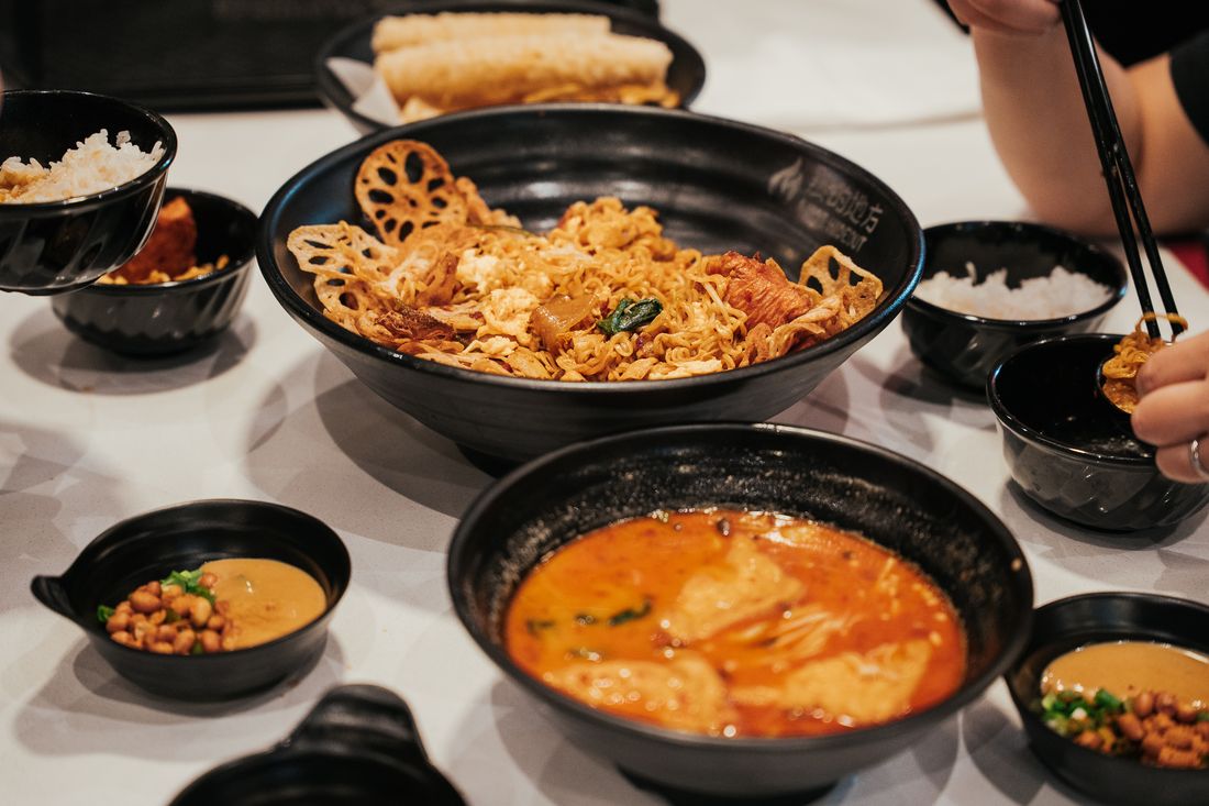 Mala stir fry and mala soup on the table with rice and peanut sauce