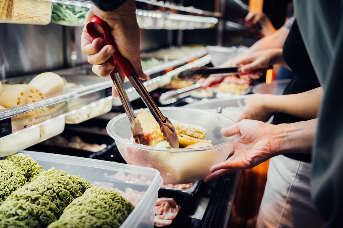 Tongs filling a bowl at the ingredient fridge